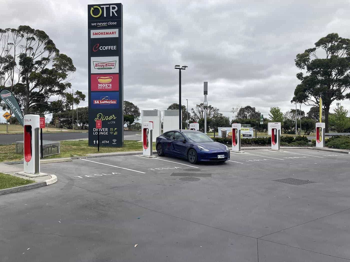 An electric car charging at a row of fast chargers beside a service station in Mount Gambier, South Australia