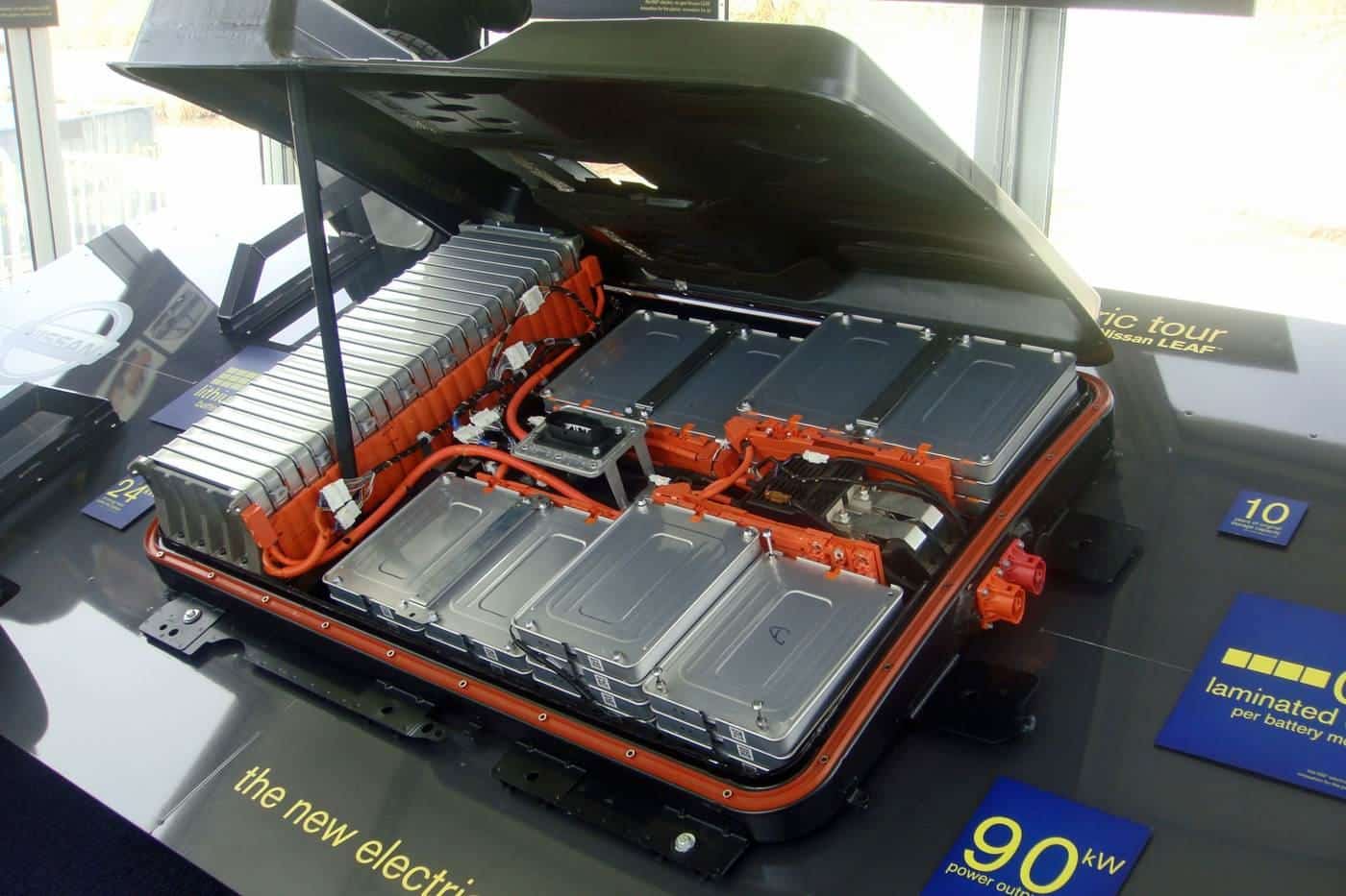 A display electric car battery pack with orange cabling and silver cell modules in a demonstration chassis