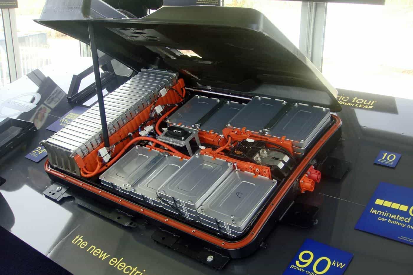 A display electric car battery pack with orange cabling and silver cell modules in a demonstration chassis