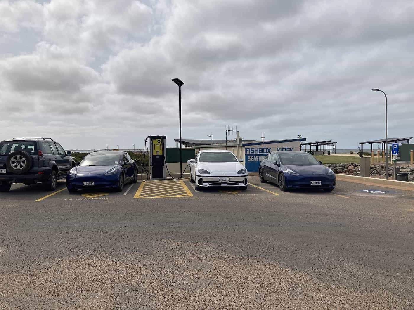 Electric cars lined up at a roadside charging station on a cloudy day in Cowell, South Australia