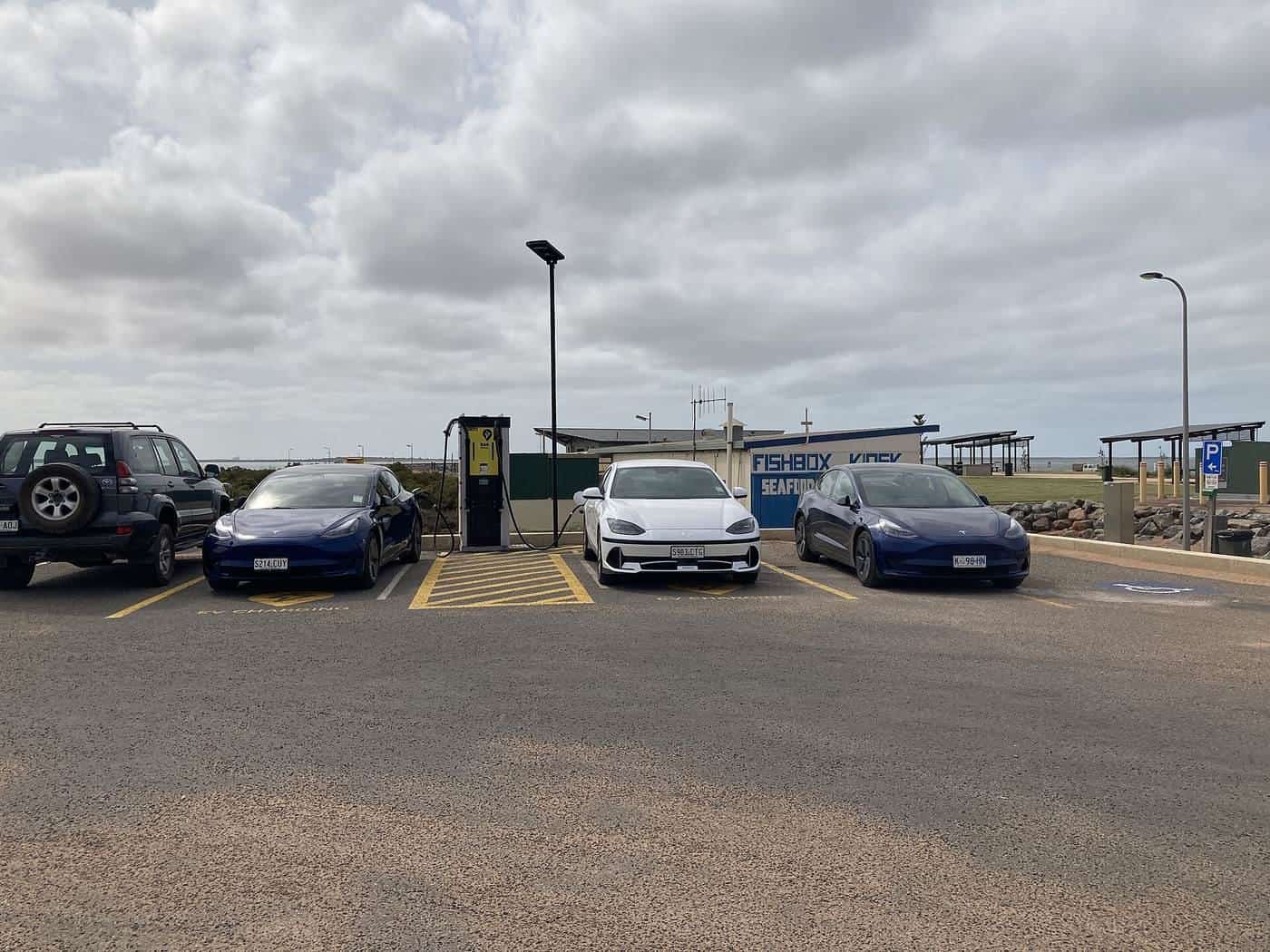 Electric cars lined up at a roadside charging station on a cloudy day in Cowell, South Australia
