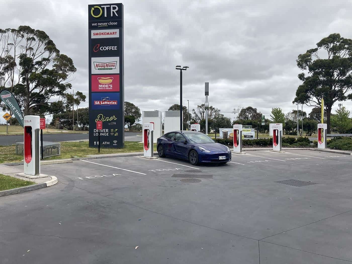 An electric car charging at a row of fast chargers beside a service station in Mount Gambier, South Australia