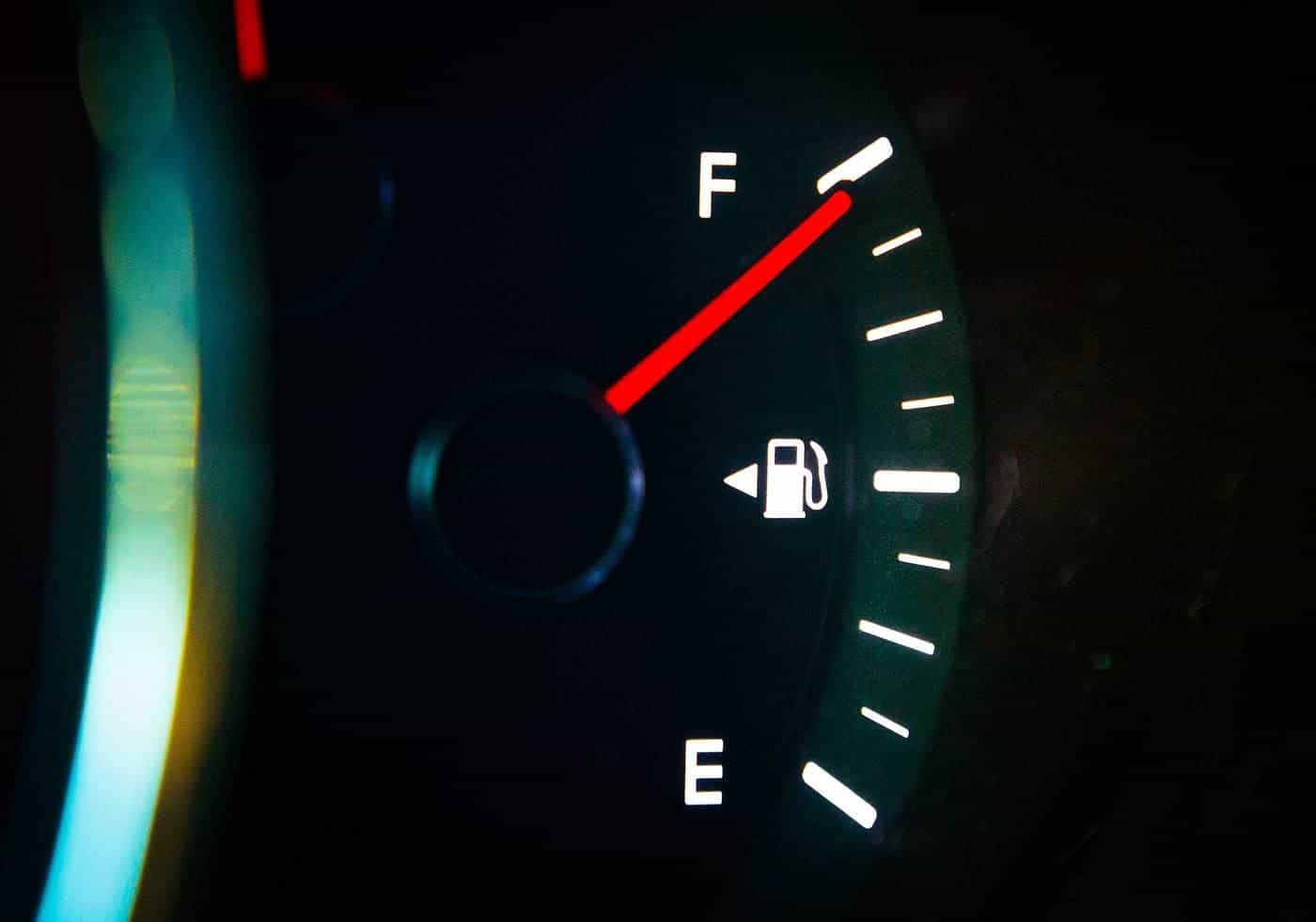 A car fuel gauge glowing at night with the needle pointing to full