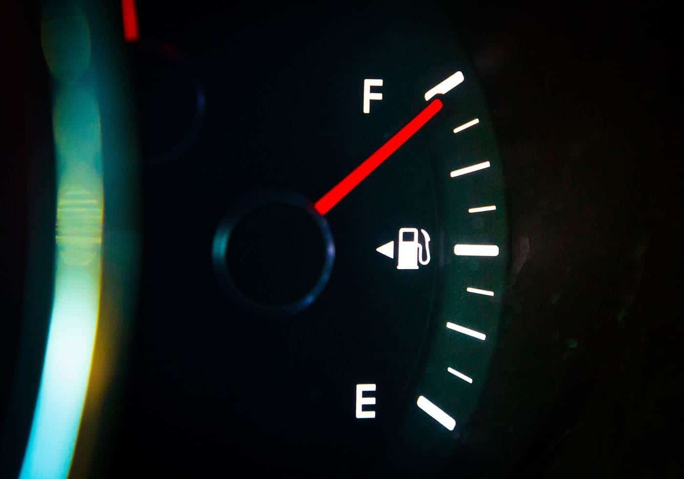 A car fuel gauge glowing at night with the needle pointing to full